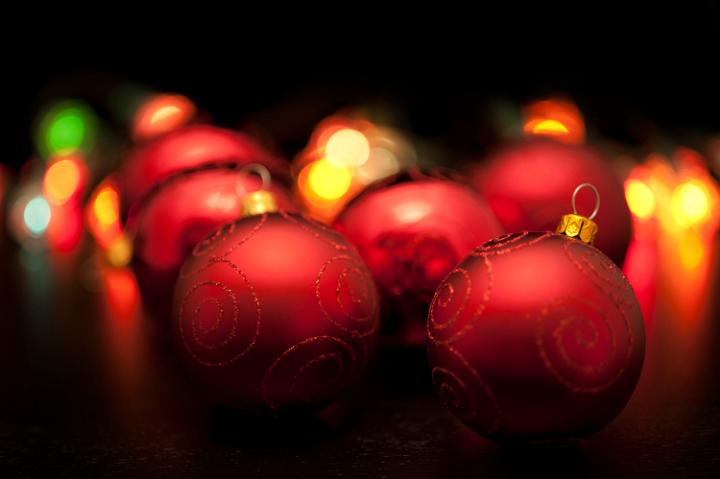 Dark colourful Christmas background or red baubles reflecting festive lights with shallow dof and blur