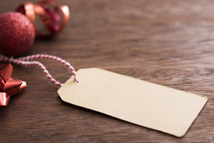 Paper label on a striped string near some red xmas baubles