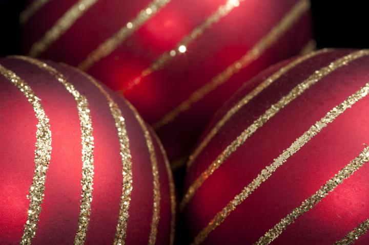 close up on three red christmas baubles with lines of gold glitter