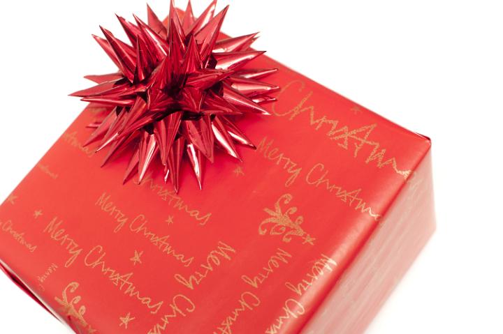 Colorful festive red Christmas gift with decorative spiky ribbon bow isolated on white viewed close up from above