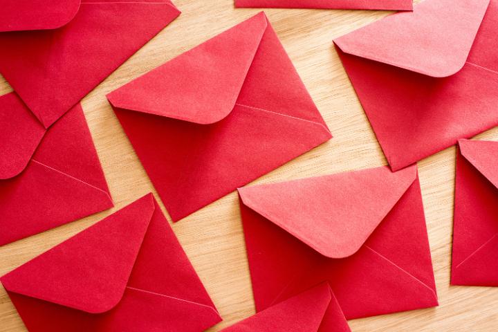 Background of festive red envelopes on a wooden table or desk conceptual of Christmas and the holiday season