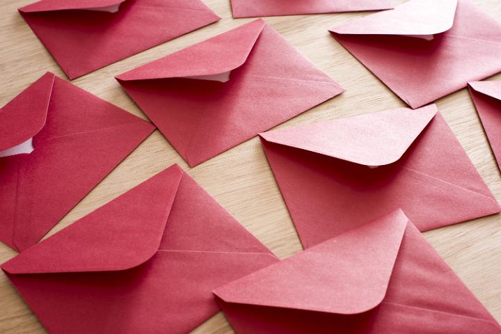 Festive red Christmas envelopes background in a communication and greeting concept lying face down over a wooden background in a close up view