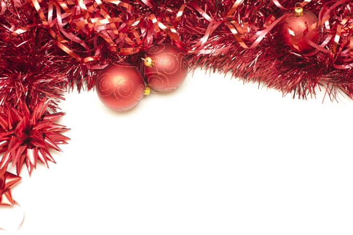 Festive border of red Christmas tinsel and baubles isolated on white with copy space for your seasonal greeting