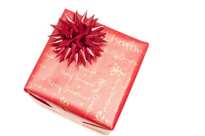 Festive red Merry Christmas gift with decorative spiky foil bow viewed from above isolated on white with copy space