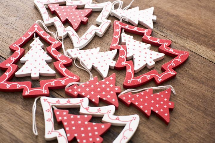 Selection of festive red and white patterned Christmas tree ornaments for celebrating Xmas lying on a wood table , close up high angle view