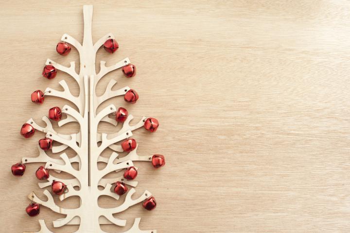 Modern festive decorations, a wooden tree decorated with red Christmas balls lying on wooden table. From above