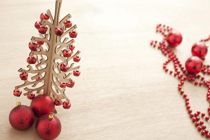 Wooden Christmas tree with red decorations on a modern table surface