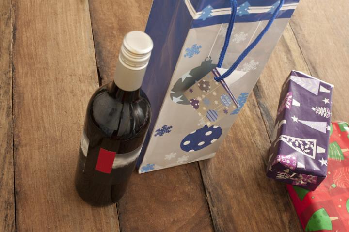 Bottle of red wine and Christmas presents on wooden table