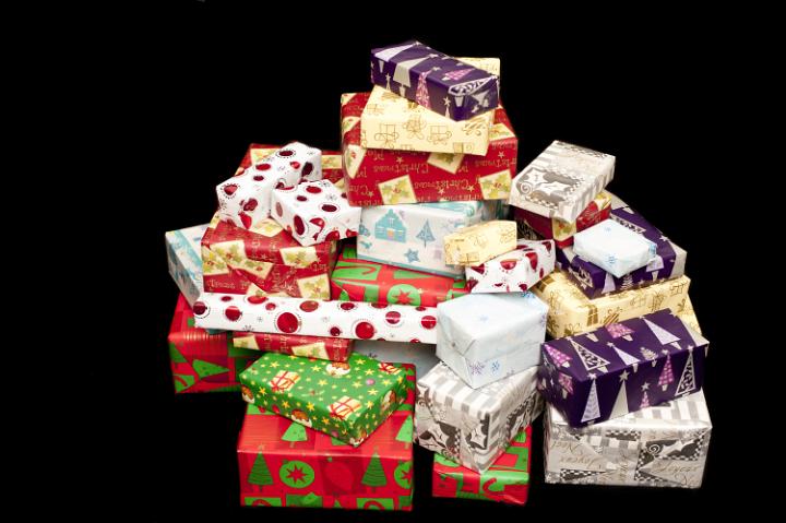 Pile of colorful Christmas gifts in assorted seasonal patterned wrapping paper on black with copy space