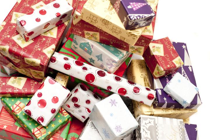 Colorful Christmas gifts background with boxes wrapped in decorative patterned seasonal paper piled in a heap on white