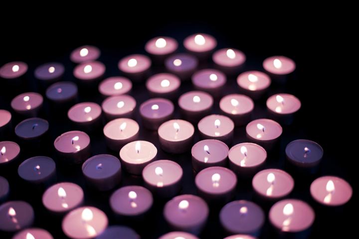 A large number of pink tinted candles burning in the darkness a symbol of hope, faith and celebration
