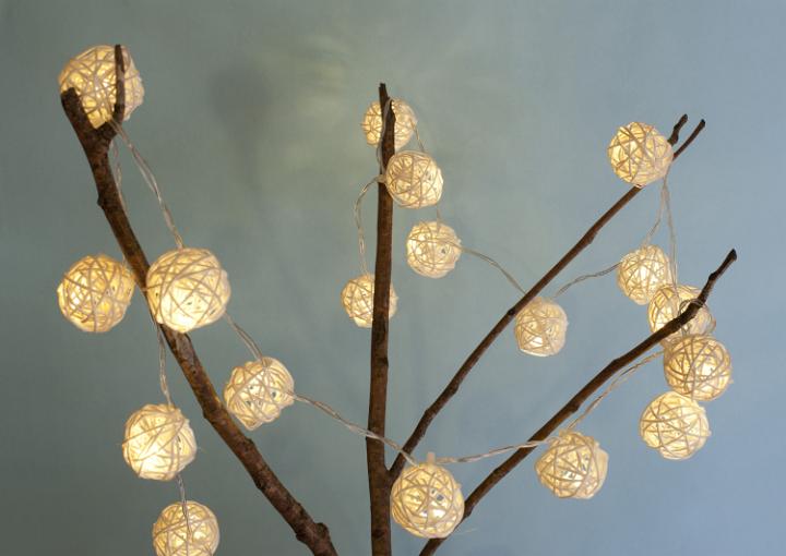 Handmade lighted garland on leafless branches against of white background